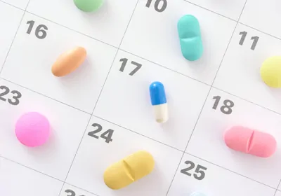 Colorful pills and capsules on a calendar background